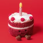Close-up of Jellycat Amuseable Cheri Cake showing the plush red velvet sponge, cream swirl topping, and cute embroidered smile.
