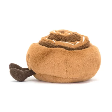 Side view of the Jellycat Amuseable Cinnamon Bun, highlighting its round, fluffy shape and cream-stitched icing drizzle.