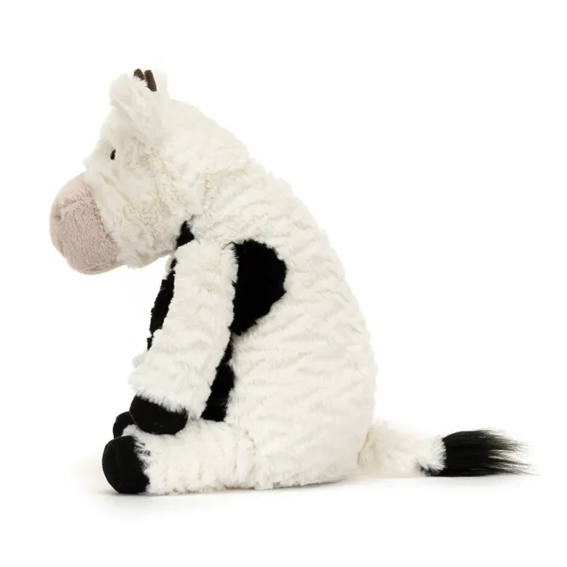 Side view of the Jellycat Mooliet Cow, highlighting its textured fur, curved horns, and fluffy tail tip.