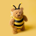 Detailed view of Jellycat Bartholomew Bear 'Bumblebee' with a focus on his adorable face, featuring shiny black eyes and a stitched smile.