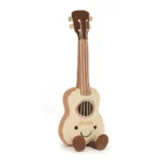 Front view of the Jellycat Amuseable Ukulele showing its cheerful face, cream front, and soft strings.