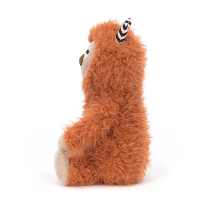 Side view of Jellycat Pip Monster showcasing its fluffy texture and striped horn detail.