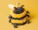 Jellycat Albee Bee plush toy with fluffy yellow and black stripes, smiling on a matching yellow background.