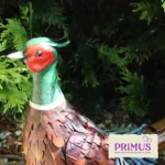 Pheasant Metal Garden Ornament close-up surrounded by green garden foliage, highlighting its red and green head detail.
