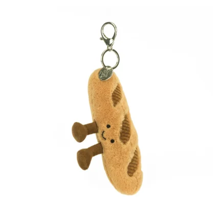 Front view of Jellycat Amuseable Baguette Bag Charm, featuring a smiling plush baguette with cordy legs and metal clasp.