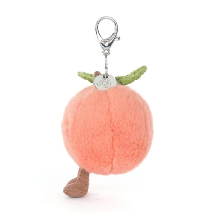 Side view of Jellycat Amuseable Peach Bag Charm showing its plush blush fur, soft cord legs and attached silver clip.