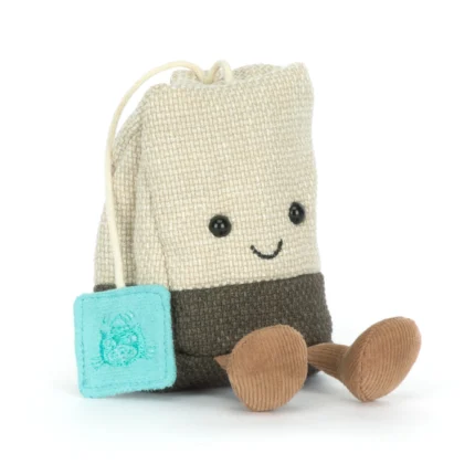 Front view of Jellycat Amuseable Steepy Tea Bag showing beige textured plush body, embroidered smile, dangling tea string, and blue tag detail.