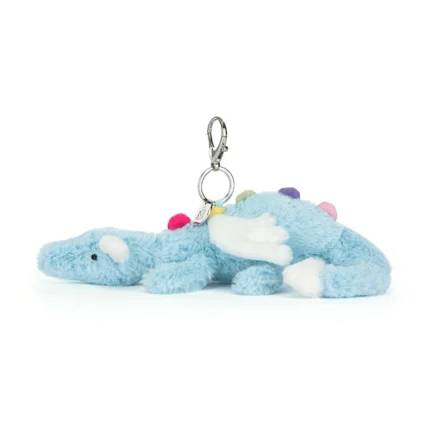 Side view of Jellycat Sky Dragon Bag Charm showing plush baby blue fur, white wings, rainbow back spikes and attached silver clip.