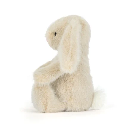 Side view of Jellycat Wheat Flufflet Bunny showing plush wheat beige fur, long floppy ear and fluffy cream tail.
